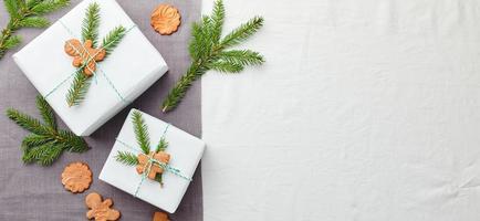 Christmas gifts wrapped in white paper and decorated with spruce sprigs and gingerbread cookies photo