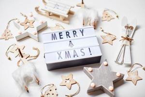 caja de luz inscripción feliz navidad y adornos de madera foto