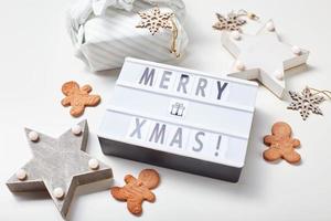 Light box inscription Merry Christmas, gifts in Japanese furoshiki style and gingerbread cookies photo