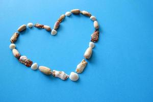 A heart from different seashells on the blue background for Valentine's Day. photo