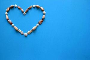 A heart from different seashells on the blue background for Valentine's Day. photo