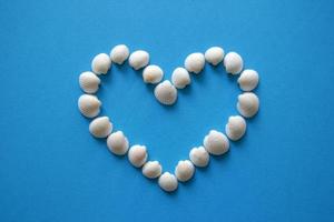 A heart from different seashells on the blue background for Valentine's Day. photo