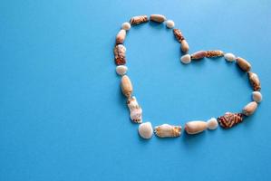 A heart from different seashells on the blue background for Valentine's Day. photo