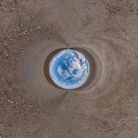 blue sphere little planet inside gravel road or field background. curvature of space photo