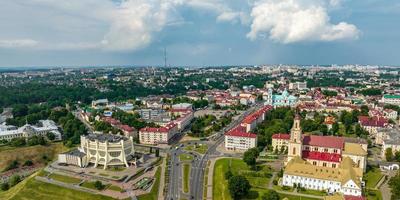 aerial panoramic view from great height on red roofs of old big city with skyscrapers and white fluffy clouds photo