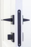 Modern black door handle on white wooden door in interior. Knob close-up elements. Door handle, fittings for interior design photo