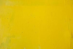 old wall painted with yellow paint with cracks and bubbles photo