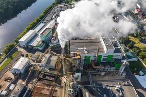 aerial panoramic view on smoke pipes of a woodworking factory on the bank of a wide river photo