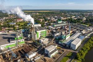 aerial panoramic view on smoke pipes of a woodworking factory on the bank of a wide river photo