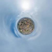 tiny planet in sky with clouds overlooking old town, urban development, historic buildings and crossroads. Transformation of spherical 360 panorama in abstract aerial view. photo