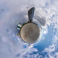 pequeño planeta en el cielo azul con nubes en el centro de la ciudad cerca de modernos rascacielos o edificios de oficinas. transformación del panorama esférico 360 en vista aérea abstracta. foto