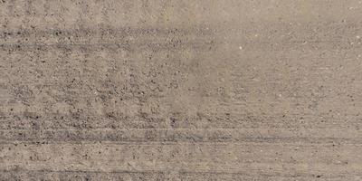 panorama of surface from above of gravel road with car tire tracks photo