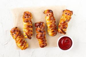 Scary sausage mummies in dough for kids party. Funny crazy Halloween food for children. photo