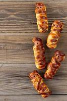 Scary sausage mummies in dough for kids party. Funny crazy Halloween food for children. photo