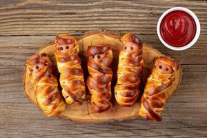 Scary sausage mummies in dough for kids party. Funny crazy Halloween food for children photo