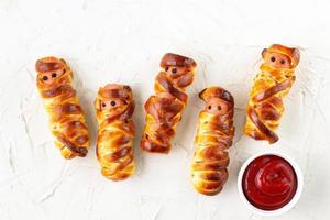 Scary sausage mummies in dough for kids party. Funny crazy Halloween food for children. photo