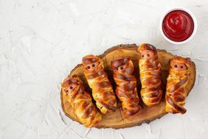 Scary sausage mummies in dough for kids party. Funny crazy Halloween food for children. photo