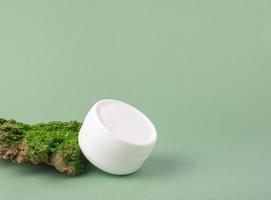 Natural skin care. Environmentally friendly cosmetics. A jar of face cream on the bark of a tree with green moss on a green background. copy space photo