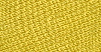 textura de suéter amarillo de punto liso con patrón. vista superior, primer plano. tejido a mano de lana o textura de tela de algodón. fondo de patrones de tejido. foto