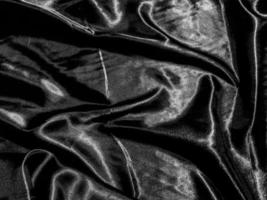 fondo de seda negra de lujo o textura satinada con ondas líquidas o pliegues ondulados. diseño de papel tapiz foto