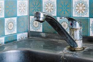 Old rusty sink faucet in kitchen. Rust streaks, calcium scale, hard water. photo