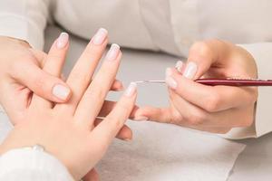 Woman receiving french manicure by beautician photo