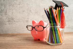 Pigging bank wearing eyeglass with colorful pencils saving bank education concept. photo