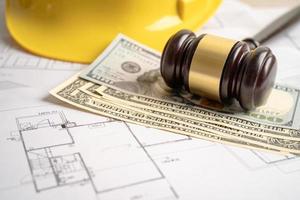 Architectural house plan project blueprint and Judge gavel hammer with yellow helmet and US dollar banknotes, Engineer and construction law and justice. photo