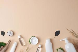 Cosmetic skin care products with flowers and wood on pastel beige background. Flat lay, copy space photo