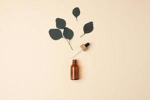 Cosmetic bottle with eucalyptus on pastel beige background. Flat lay, copy space photo