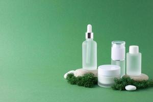 Cosmetic skin care products with stones and moss on green background. Close up, copy space photo