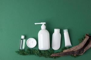 composición cosmética con productos para el cuidado de la piel, musgo y madera sobre fondo natural verde oliva. endecha plana, espacio de copia foto