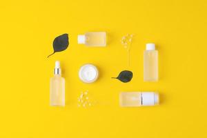 Skin care products on yellow background with flowers, eucalyptus. Flat lay. photo