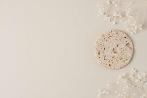 Cosmetic background with flowers and stone podium on pastel beige. Flat lay, copy space photo