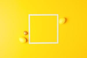 Easter yellow eggs on a yellow background with white square. Flat lay, copy space. photo