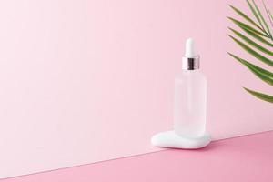 Cosmetic bottle with stone and palm leaf on pink background. Close up, copy space photo