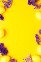 huevos amarillos de Pascua con flores de color púrpura sobre fondo amarillo. endecha plana, espacio de copia. foto