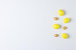 Easter yellow and golden eggs on white background. Flat lay, copy space. photo