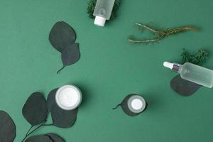 Cosmetic skin care products with eucalyptus and moss on green background. Flat lay, copy space. photo