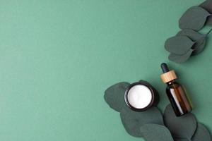 productos cosméticos para el cuidado de la piel con eucalipto sobre fondo verde. endecha plana, espacio de copia foto