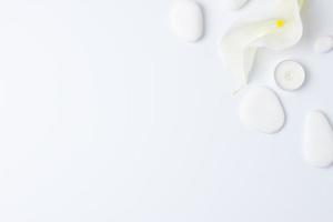 Spa background with white stones, candles and white flower on white. Flat lay,copy space photo