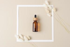 White frame with cosmetic bottle on beige background. Flat lay. photo