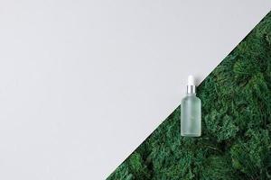 Cosmetic bottle with moss on white background. Flat lay, copy space. photo