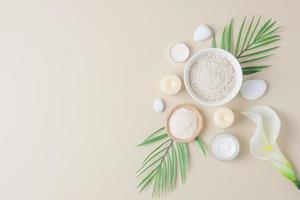 Spa background with skin care products, stones, candles and palm leaves on pastel beige. Flat lay,copy space photo