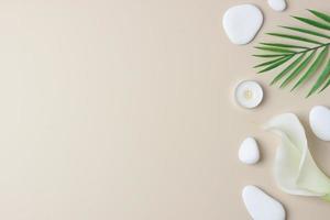 Spa background with white stones, candles, palm leaf and white flower on pastel beige. Flat lay,copy space photo