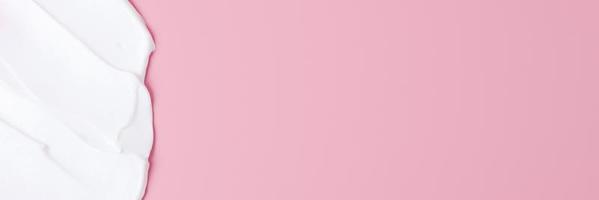 Cosmetic background with white cream on pink. Flat lay, copy space photo