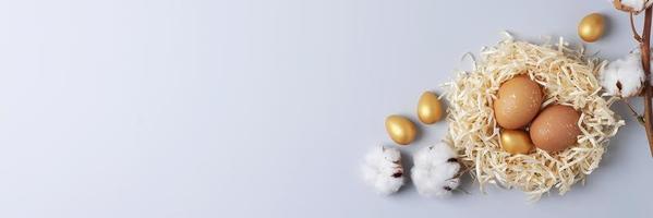 Nest with easter eggs with flowers on grey background. Flat lay, copy space photo