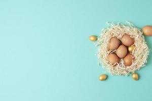 Nest with easter eggs with flowers on blue background. Flat lay, copy space photo