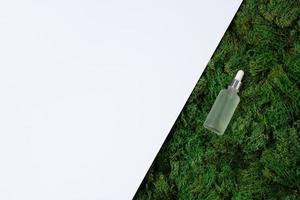 Cosmetic bottle with green moss natural background on white. Flat lay, copy space photo