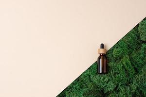 Cosmetic bottle with moss on beige background. Flat lay, copy space. photo